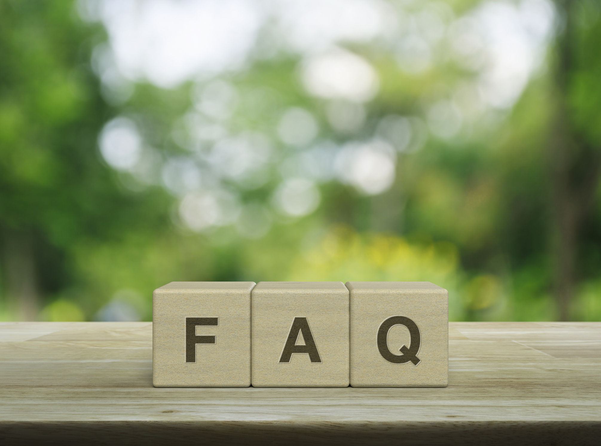 FAQ letter on block cubes on wooden table over blur green tree in park, Frequently asked questions.